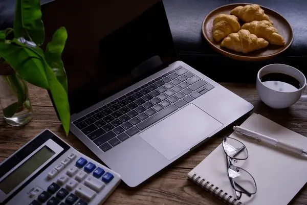Twee mensen plannen aan tafel met notitieboeken en koffiekoppen